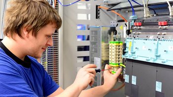 Ein Elektroniker der an einer Reihenklemme schraubt