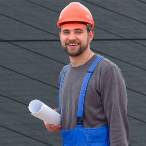 Ein Mann in Arbeitskleidung, hinter Ihm ist eine Photovoltaikanlage zu sehen
