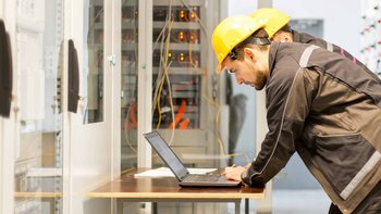 Zwei Elektroniker an einem Laptop in einem Serviceraum