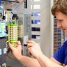 Ein Elektroniker der an einer Klemmverbindung schraubt