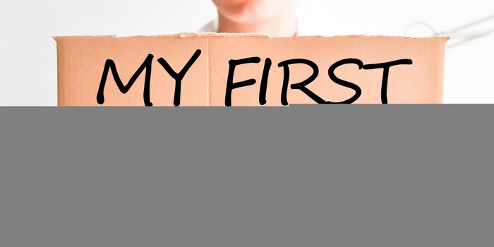 Zwei Hände die ein stück Pappe hoch halten auf dem My First Day! steht