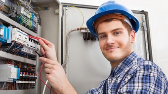 Ein junger Elektroniker überprüft einen Verteilerkasten 