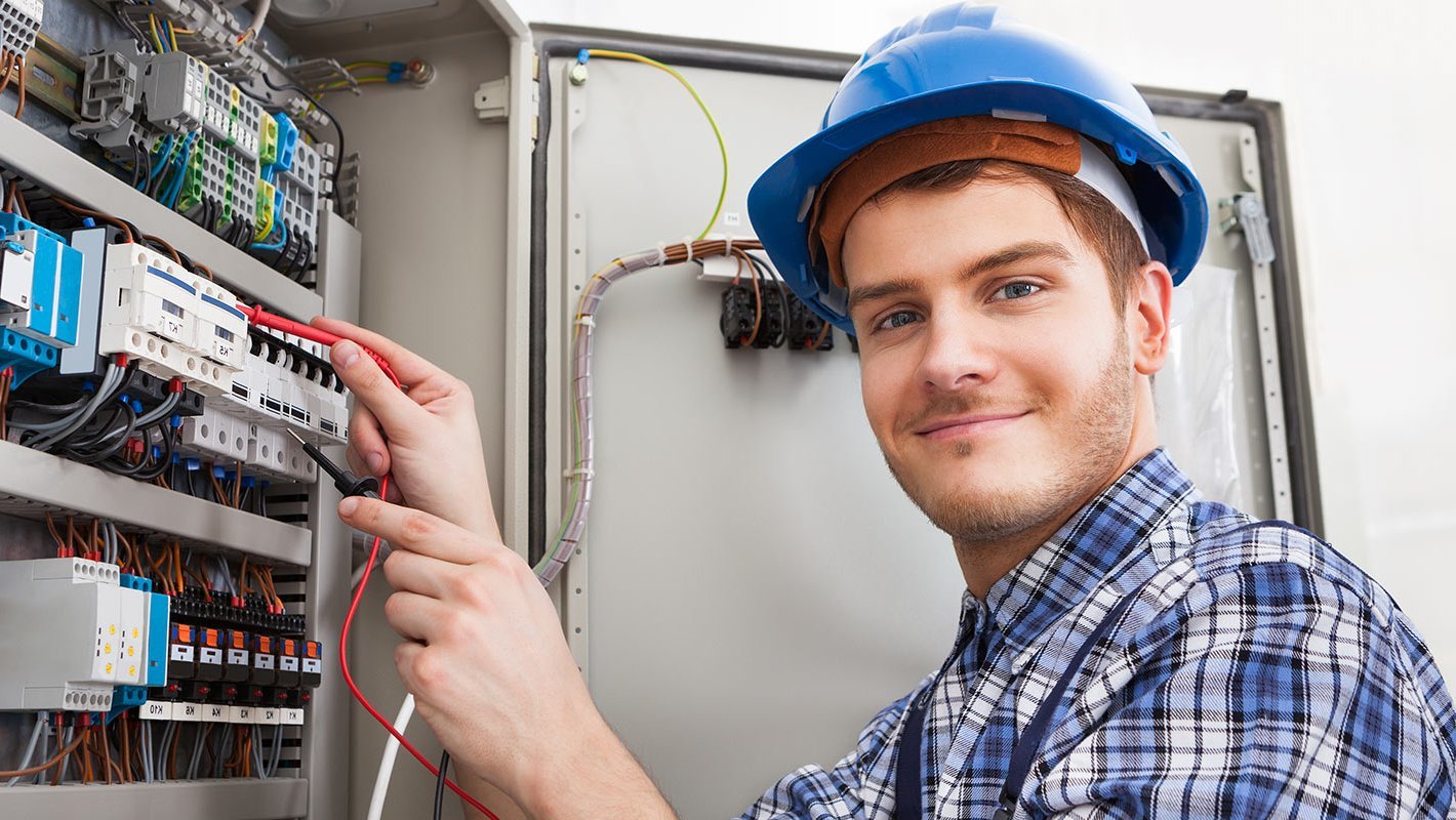 Ein junger Elektroniker überprüft einen Verteilerkasten