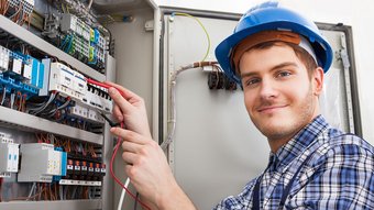 Ein junger Elektroniker überprüft einen Verteilerkasten 